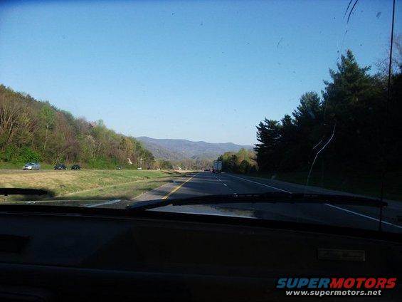 View from inside a vehicle looking out at a highway with mountains in the distance