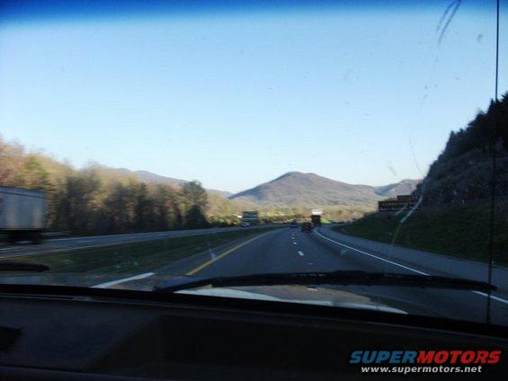 Highway view from inside a vehicle, with mountains and other vehicles on the road