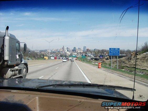 Highway scene with truck, city skyline, and exit sign