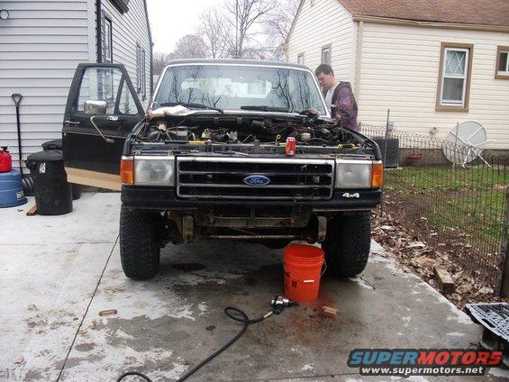 1990 Ford Bronco front view, hood open, parked on driveway with tools nearby