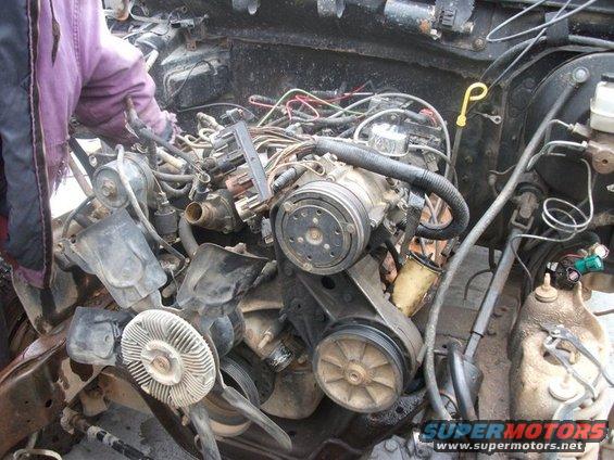 Engine bay with a person working on the motor and wiring