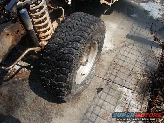 Front tire and suspension of a vehicle, showing a large off-road tire and coilover shock