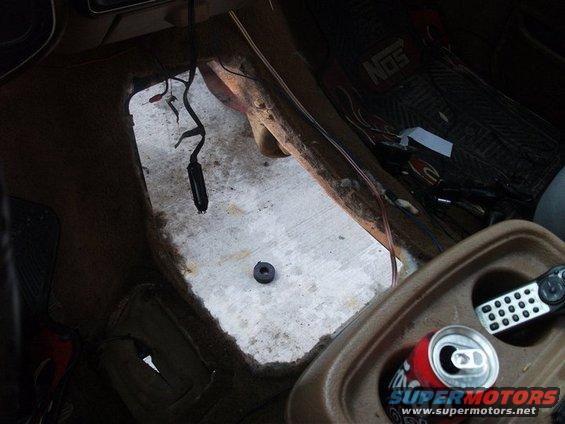 Interior floor with exposed metal, wiring, and a cut-out section. A soda can and remote are in the center console