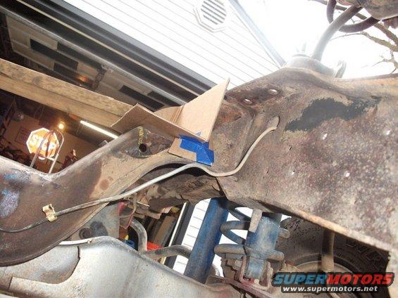 close-up of rusty vehicle frame with blue shock absorber and spring