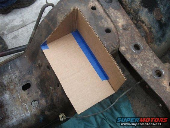 Cardboard template taped to a rusty vehicle frame