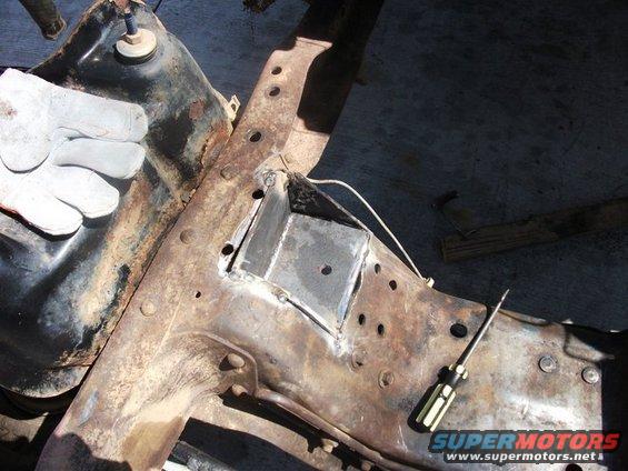 welding a metal bracket onto a heavily rusted vehicle frame, with a gloved hand visible