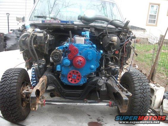 Disassembled vehicle front end with a bright blue engine installed