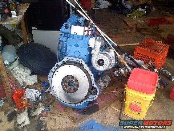 blue engine with turbo and flywheel, fishing rods, buckets, and other garage items