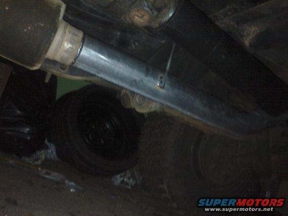 Underneath view of a vehicle's exhaust pipe and a tire