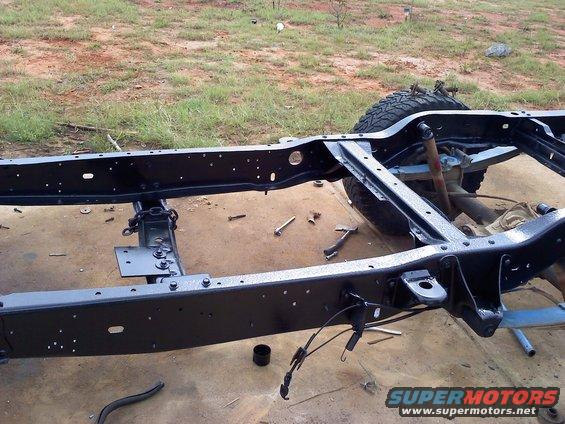 Black painted vehicle frame with suspension components and a tire visible