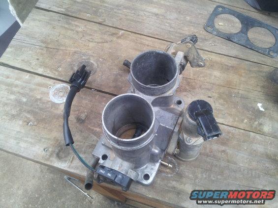 Throttle body with dual bores and electrical connectors on a wooden surface