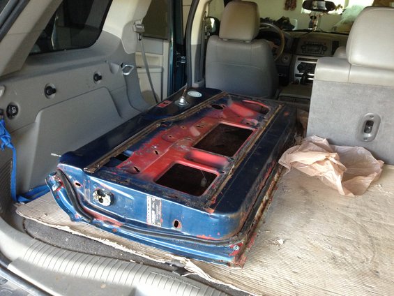 Blue car door with red primer, lying inside a vehicle's cargo area