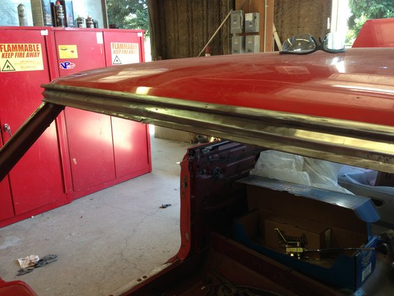 Red car roofline and interior in a garage with red cabinets. Some boxes are visible inside the car
