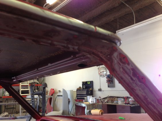 Close-up of car's A-pillar and roof structure during restoration, showing primer and some bodywork