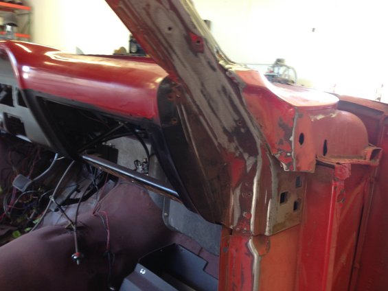 Car interior showing red painted dashboard and exposed metalwork, with wiring visible