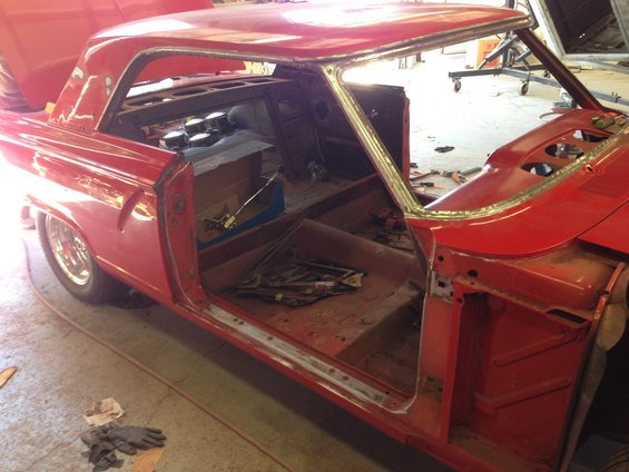 1964 Ford Fairlane coupe interior during restoration, showing stripped door panels and dashboard