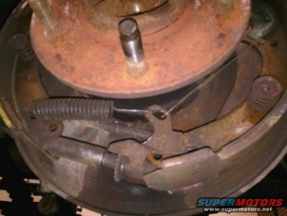 Drum brake assembly with rusted components and a Supermotors.net watermark