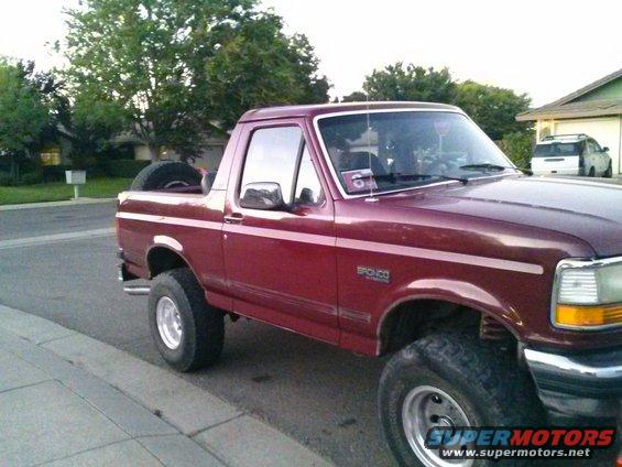 Red 1992 Ford Bronco parked curbside, showing its side and front quarter panel