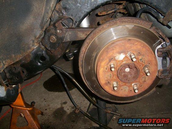close-up of rusty rear brake rotor and caliper assembly on a car