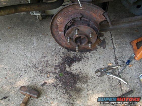 close-up of rusty rear brake assembly with tools on concrete