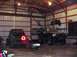 1992 Ford Bronco - Two off-road vehicles are parked inside a barn, one with a prominent triangular taillight.