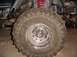 1992 Ford Bronco - Close-up of a large off-road tire and suspension components of a vehicle in a garage.