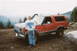 1983 Ford Bronco - A man poses with his red Ford Bronco, equipped with a snorkel, in an outdoor, mountainous setting.