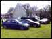 1968 Ford Mustang - A black 1968 Ford Mustang is parked on the lawn in front of a house, alongside two other cars.