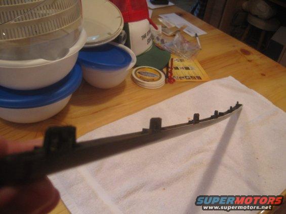 Black plastic trim piece with mounting clips, held in hand over a white towel
