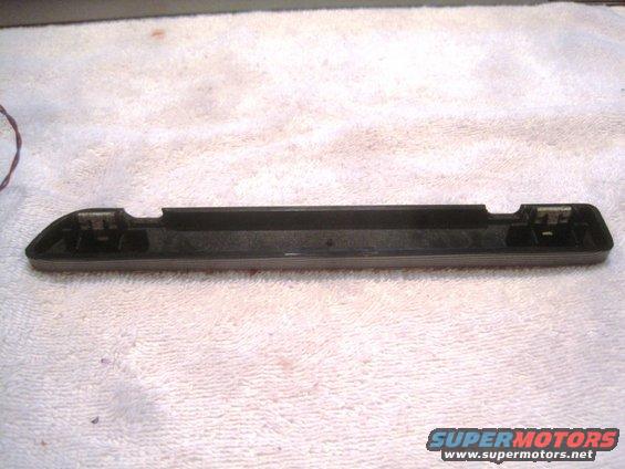 Black plastic trim piece with metal clips on a white towel. Supermotors.net logo at bottom right