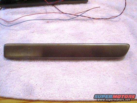 Bronze car door handle trim piece with horizontal lines, resting on a white towel