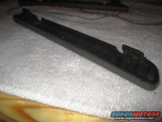 Black plastic trim piece with visible wires attached