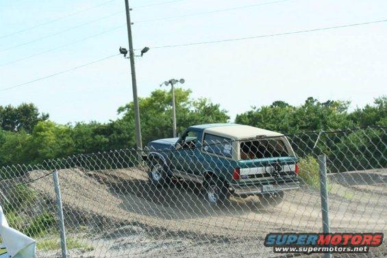 Green Ford Bronco driving on a dirt track