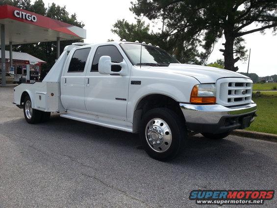 White crew cab tow truck with flatbed body parked at a Citgo gas station