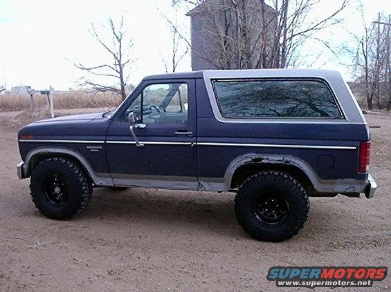 Side view of a 1985 Ford Bronco with large tires and a silver top