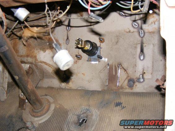 Close-up of vehicle interior showing wiring harness, ignition switch, and steering column base