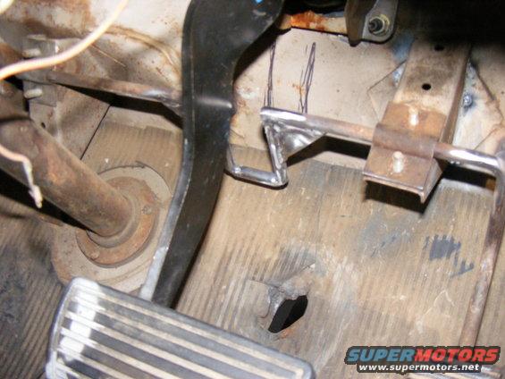 Metal pedals and rusty floorboard in a vehicle interior