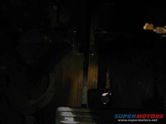 Interior view of pedals and floor mat in a dark vehicle