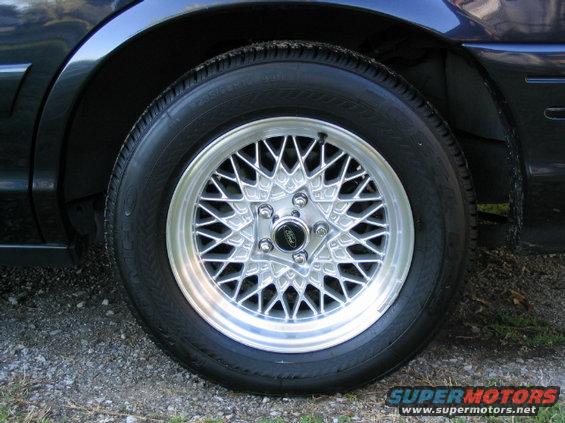 Close-up of a 1999 Ford Crown Victoria wheel with a mesh-spoke design and a black center cap with a Ford logo