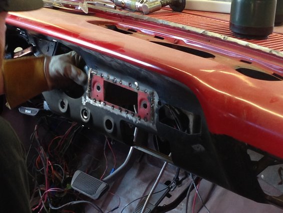 Red dashboard interior during repair, showing exposed wiring and metalwork