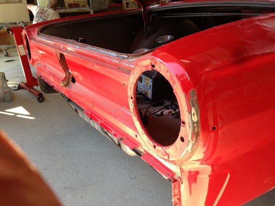 red car's trunk area and rear quarter panel, missing taillight housing. A battery charger is visible inside
