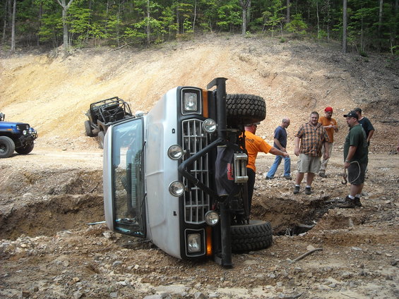 White 1979 Ford F-150 on its side with people around