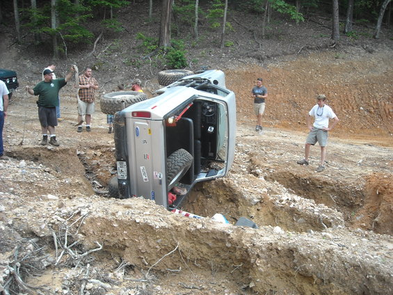 Silver 1979 Ford F-150 on its side in a ditch with people around