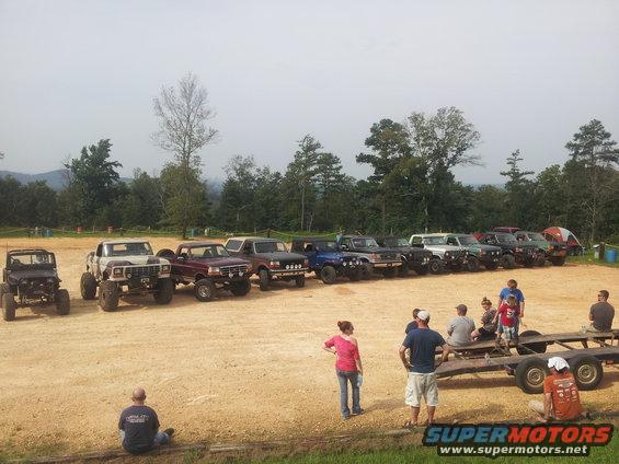 Line of lifted trucks and SUVs parked on dirt lot