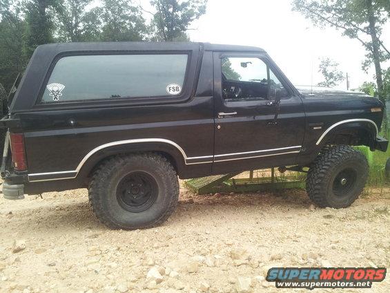 Black SUV side view, lifted suspension, oval sticker on rear window