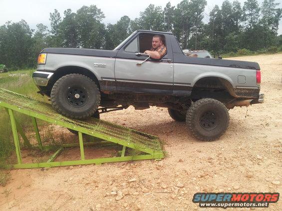 Ford Bronco with lifted suspension and large tires climbing a green metal ramp