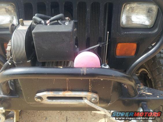 Front of a Jeep Wrangler with a winch, aftermarket bumper, and a pink object on the grille