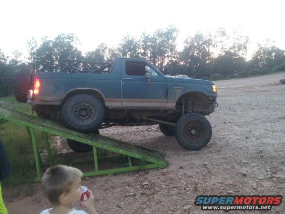 Dark green SUV with roll cage and large tires on a ramp