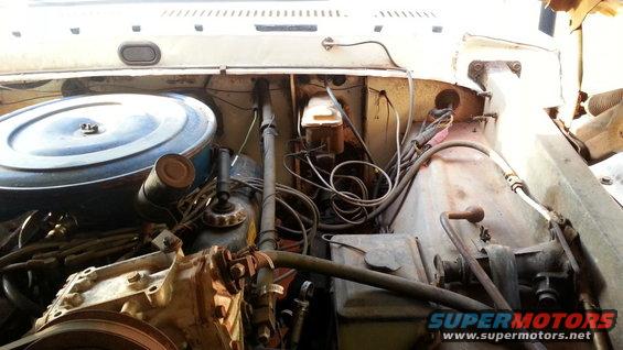Engine bay with air cleaner, hoses, and wiring visible
