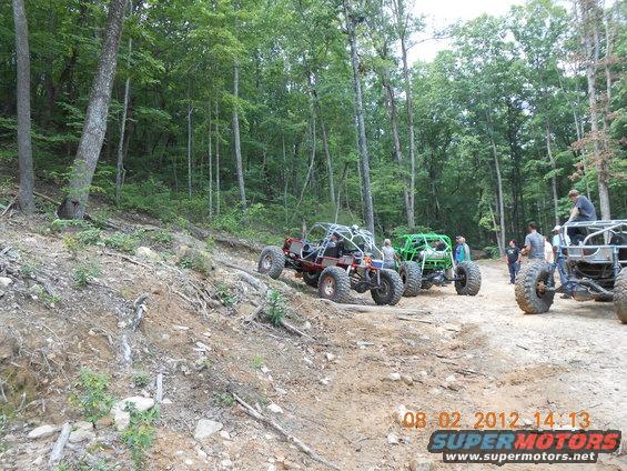 Red and green off-road buggies on a dirt path in a forest